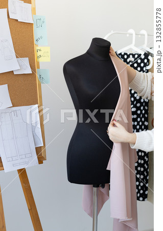 Designer draping light fabric on mannequin in creative atelier. Style, process, and inspiration in fashion craftsmanship and clothing design. Designer draping light fabric on mannequin in creative atelier. Style, process, and inspiration in fashion craftsmanship and clothing design. 132855778
