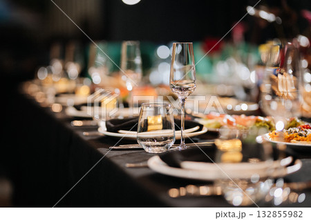 Closeup of elegant banquet table with glasses and black napkins in soft bokeh light 132855982
