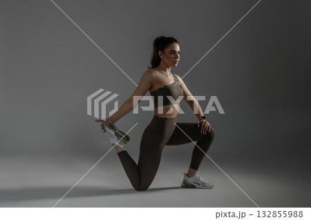 Dedicated athlete stretches in a minimalist studio setting during a focused training session Dedicated athlete stretches in a minimalist studio setting during a focused training session 132855988