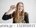 Smiling young woman holds keychain while showing excitement for new beginnings in a bright, minimalistic setting 132856015