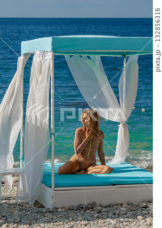 Woman beach cabana, a woman sits on a tranquil pebble beach cabana by the blue sea 132856316