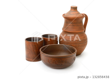 Set of traditional earthenware pottery including jug, cups, and bowl made of brown clay with carved patterns isolated on white background Set of traditional earthenware pottery including jug, cups, and bowl made of brown clay with carved patterns isolated on white background 132856438