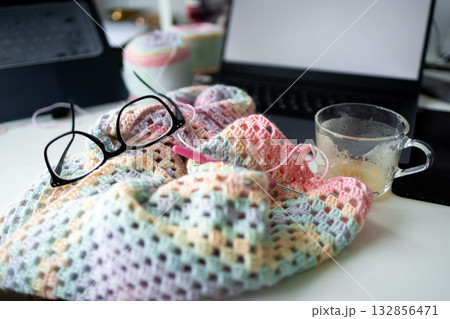 Cozy knitting scene with glasses and coffee near laptop on craft table 132856471