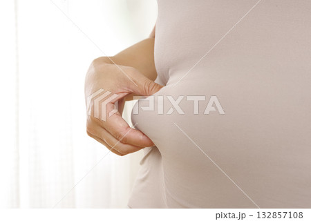 ぽっこりお腹と皮下脂肪を気にする女性 ぽっこりお腹と皮下脂肪を気にする女性 132857108