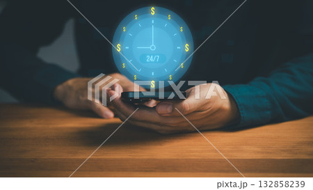 24/7 online payment and mobile banking concept with hands holding smartphone and digital clock surrounded by dollar symbol. Real-time finance, fintech services, money transfer and global transactions. 24/7 online payment and mobile banking concept with hands holding smartphone and digital clock surrounded by dollar symbol. Real-time finance, fintech services, money transfer and global transactions. 132858239