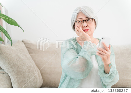 スマホを見ながら,困る,考えるグレイヘアーのシニア女性（詐欺,還付金詐欺,架空請求） 132860287