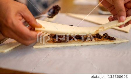 Close-up of baking process with croissant dough and chocolate filling, homemade dessert preparation concept Close-up of baking process with croissant dough and chocolate filling, homemade dessert preparation concept 132860698
