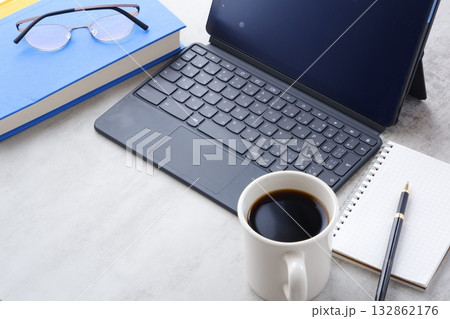 コーヒーを飲みながら、キーボードを接続したタブレット端末とメモ帳、ペンで、デスクワーク中のイメージ 132862176