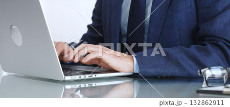 Professional businessman working on laptop computer, typing on keyboard in modern office, managing business tasks. Business people concept Professional businessman working on laptop computer, typing on keyboard in modern office, managing business tasks. Business people concept 132862911