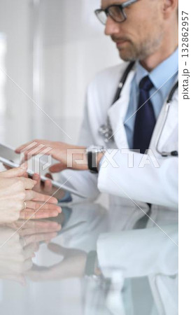 Male doctor consulting female patient, discussing diagnosis and medical history with digital tablet in clinic. Medicine and health care 132862957