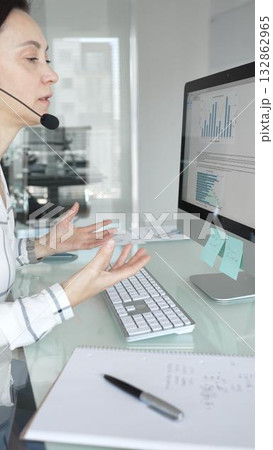 Female call center agent wearing a headset, assisting customers remotely and participating in a virtual office meeting. Professional customer support and business services 132862965