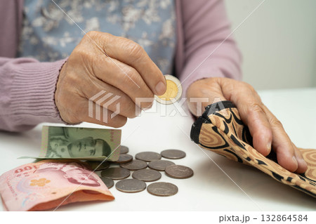 Asian senior or elderly old lady woman holding counting coin money in bag. Poverty, saving problem in retirement. 132864584