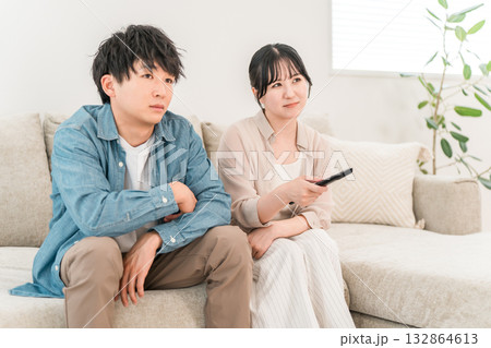 家のリビングでソファーに座りテレビを見る若いアジア人夫婦,カップル（つまらない,テレビ離れ） 132864613
