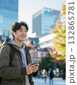 秋の街角でスマートフォンとワイヤレスイヤホンを操作する若者 132865781