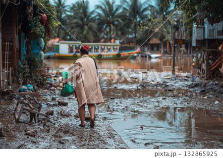barefoot woman walking flooded city, buildings under water and mud, village underwater after heavy tropical rain and typhoon, consequences with dirt on street, Hoi An, Vietnam 132865925