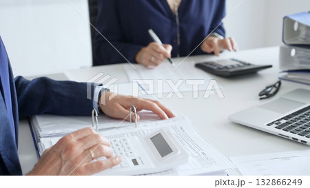 Close up of male accountant hands using calculator and collaborating with female colleague in a modern office, calculating taxes and analyzing financial data. Audit and taxes in business Close up of male accountant hands using calculator and collaborating with female colleague in a modern office, calculating taxes and analyzing financial data. Audit and taxes in business 132866249