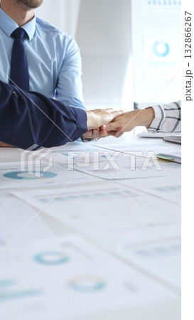 Teamwork and business collaboration with colleagues joining hands over financial charts, symbolizing unity, partnership, success, and strategic corporate planning 132866267