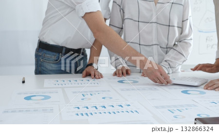 Professional team reviewing financial charts and graphs, working together in modern office environment, discussing strategic improvements. Business people concept 132866324