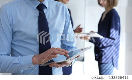 Businessman hands holding and using a digital tablet for work, navigating information and checking data during a modern corporate meeting Businessman hands holding and using a digital tablet for work, navigating information and checking data during a modern corporate meeting 132866411
