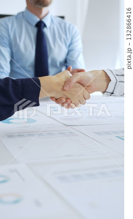 Business woman partners are shaking hands in office with financial charts, laptop and reports on table, symbolizing success, teamwork and agreement. Handshake concept Business woman partners are shaking hands in office with financial charts, laptop and reports on table, symbolizing success, teamwork and agreement. Handshake concept 132866416
