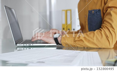 Man working on laptop, typing on keyboard in office, managing business documents and modern technology. Audit and taxes in business 132866495