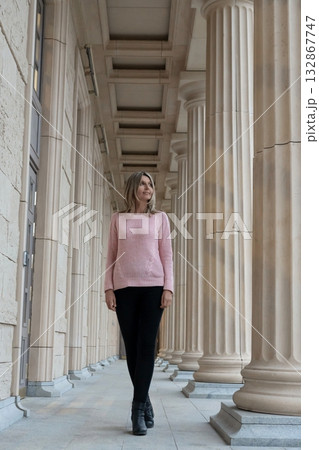 Woman walking columns architecture passage elegant female business person looks away Woman walking columns architecture passage elegant female business person looks away 132867747
