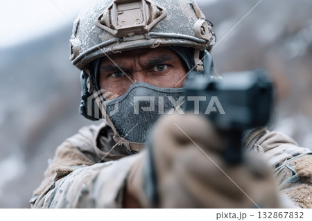 Soldier aiming a sidearm in a snowy mountainous environment during a tactical exercise 132867832