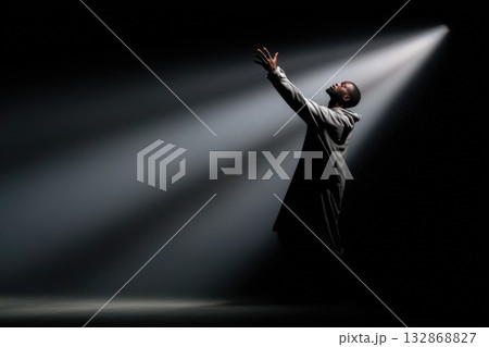 Performer reaches for his shadow under dramatic stage lighting during a captivating moment 132868827