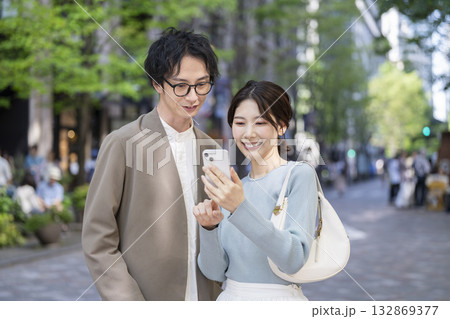 スマートフォンを見る笑顔の30代の男女 132869377