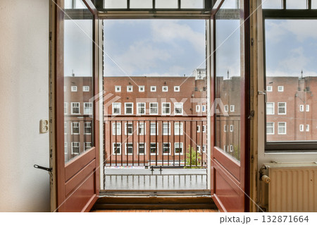 A vibrant view from an open window featuring red frames. The scene showcases an urban environment with buildings and a balcony railing. A vibrant view from an open window featuring red frames. The scene showcases an urban environment with buildings and a balcony railing. 132871664