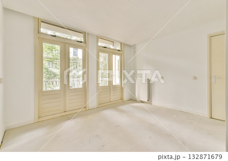 A spacious, bright, and minimalist interior featuring large windows that invite natural light. The clean lines and uncluttered design promote a serene ambiance. 132871679