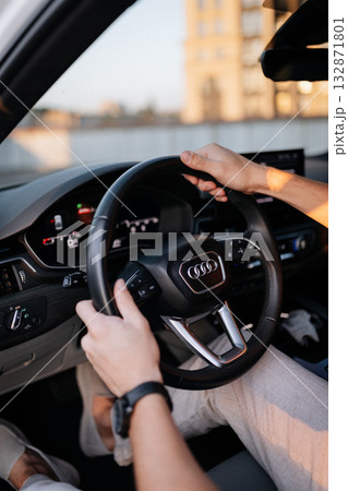 Man driving modern car at sunset, closeup of hands on steering wheel 132871801