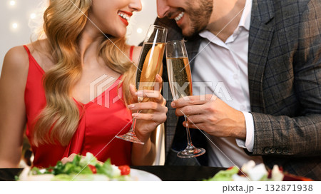 Champagne glasses in hands of unrecognizable couple at romantic dinner. Valentine's Day celebration, loving pair dining in restaurant Champagne glasses in hands of unrecognizable couple at romantic dinner. Valentine's Day celebration, loving pair dining in restaurant 132871938