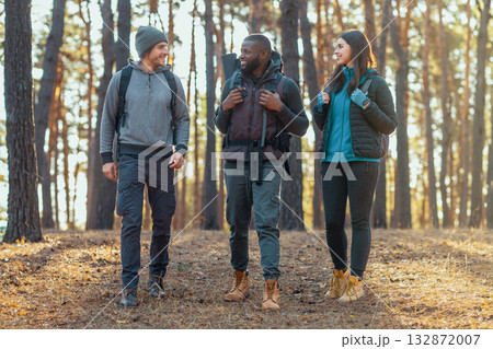 Active young mixed race people backpacking at countryside, having conversation while walking 132872007