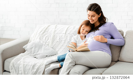 Happy family pregnant mother and preschooler daughter spending time together at home, reading book Happy family pregnant mother and preschooler daughter spending time together at home, reading book 132872064
