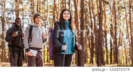 Smiling multiethnic hikers looking at camera over pine forest background, free space 132872574