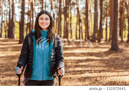 Happy girl smiling at camera while multiracial guys discussing route, hiking by forest 132872641
