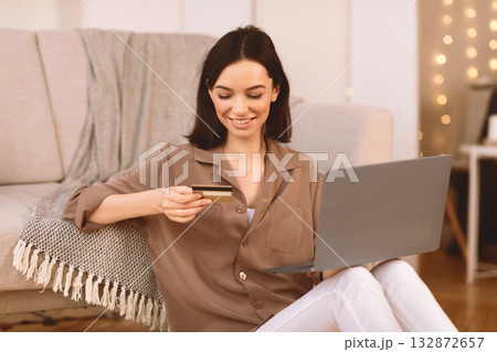 Joyful European Girl Doing Online Shopping Using Laptop Computer And Credit Card Sitting On The Floor. Copyspace Joyful European Girl Doing Online Shopping Using Laptop Computer And Credit Card Sitting On The Floor. Copyspace 132872657