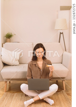 Online Store. Happy young woman doing shopping via internet using laptop and credit card, sitting on floor, copyspace Online Store. Happy young woman doing shopping via internet using laptop and credit card, sitting on floor, copyspace 132872725