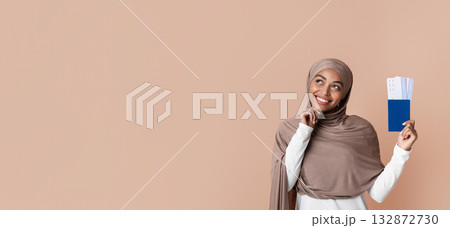 Vacation Plans. Pensive Black Muslim Girl In Hijab Holding Passport With Tickets And Dreamy Looking Upwards, Yellow Studio Background, Copy Space 132872730