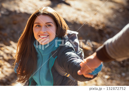 Portrait of happy young woman outstretching hand to man while hiking at forest 132872752