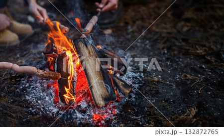 Tourism, active rest concept. Cropped of international hikers frying sausages on sticks while camping 132872765