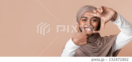 Happy Black Muslim Girl In Headscarf Making Frame With Fingers, Capturing Photo, Framing Face, Standing Over Yellow Background, Closeup 132872802