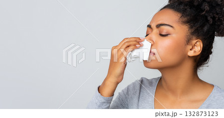 Afro woman touching her nose with napkin, bleeding or having runny nose, free space 132873123