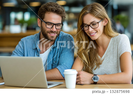 Young Couple Working Together Confidently on Laptop in Modern Cozy Workspace, Sharing Ideas and Digital Collaboration 132875698