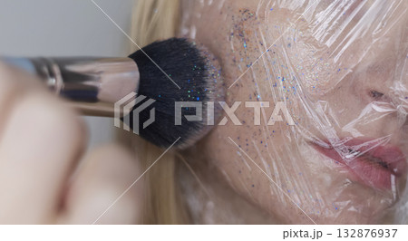 Microplastics in cosmetics. A woman applied a care cream to her skin, now it is covered with plastic particles and microbeads. Cosmetics toxicity concept Microplastics in cosmetics. A woman applied a care cream to her skin, now it is covered with plastic particles and microbeads. Cosmetics toxicity concept 132876937
