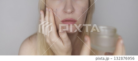 Microplastics in cosmetics. A woman applied a care cream to her skin, now it is covered with plastic particles and microbeads. Cosmetics toxicity concept Microplastics in cosmetics. A woman applied a care cream to her skin, now it is covered with plastic particles and microbeads. Cosmetics toxicity concept 132876956
