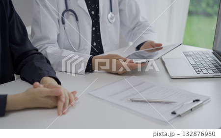 Doctor and a patient in clinic. The female physician is using tablet computer for filling up medication history record form, close up of woman hands. Medicine and science 132876980