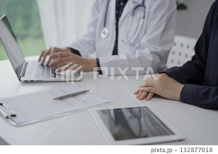 Doctor and a patient in clinic. The female physician is using laptop computer for filling up medication history record form, close up. Medicine and science 132877018
