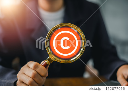 Close-up of a magnifying glass focusing on a copyright symbol, emphasizing intellectual property and legal protection. Close-up of a magnifying glass focusing on a copyright symbol, emphasizing intellectual property and legal protection. 132877066